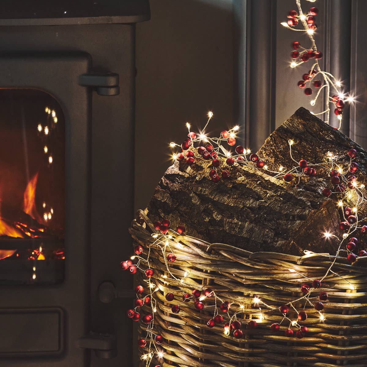 Rustic wicker basket with textured logs, red berries, and fairy lights