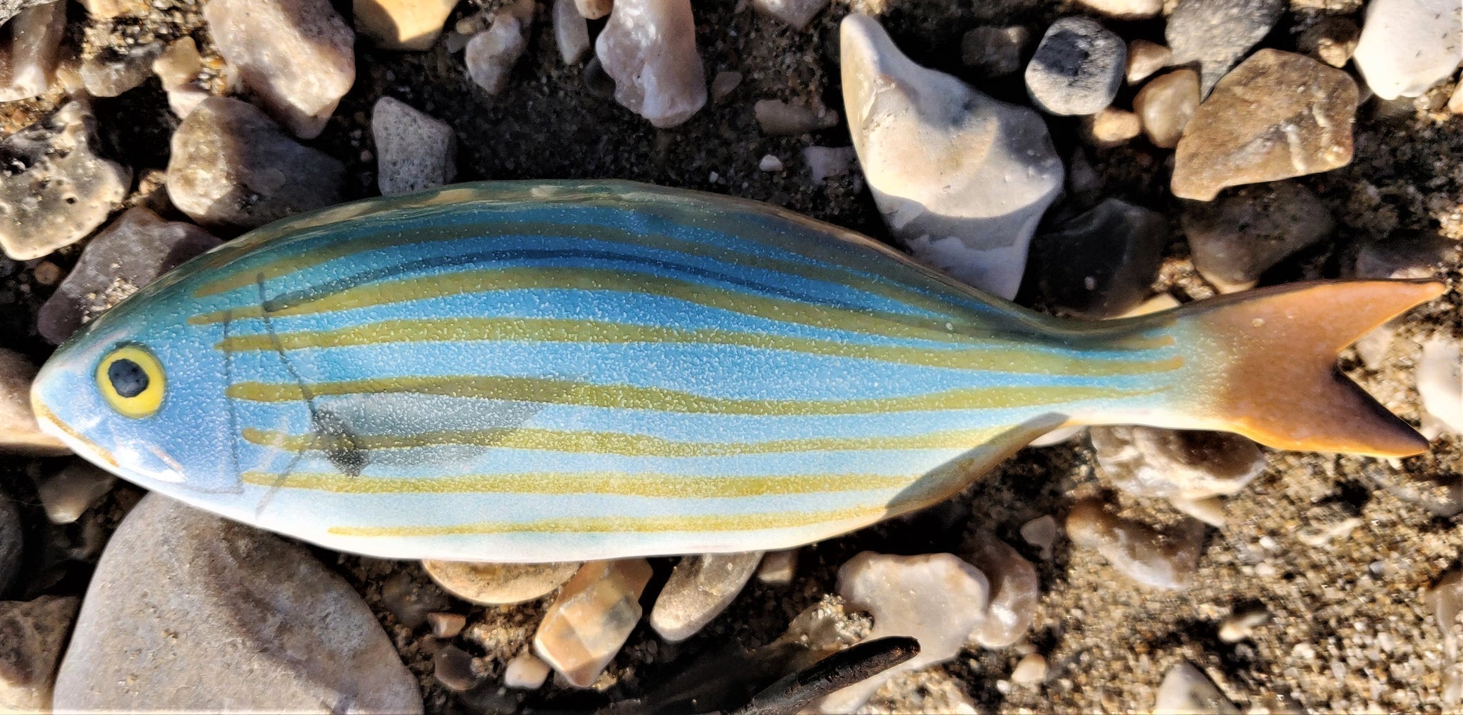 Vibrant blue yellow striped Ceramic Goldline Fish Wall Art on pebbles