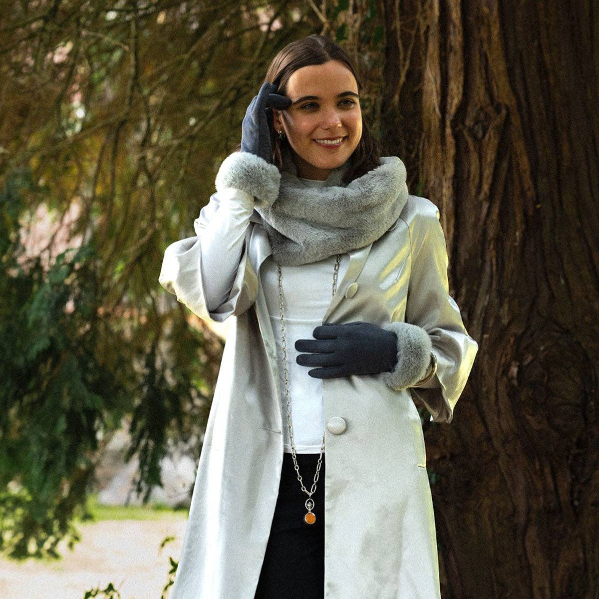 Woman in silver satin coat with fur cuffs and salmon pink faux fur snood