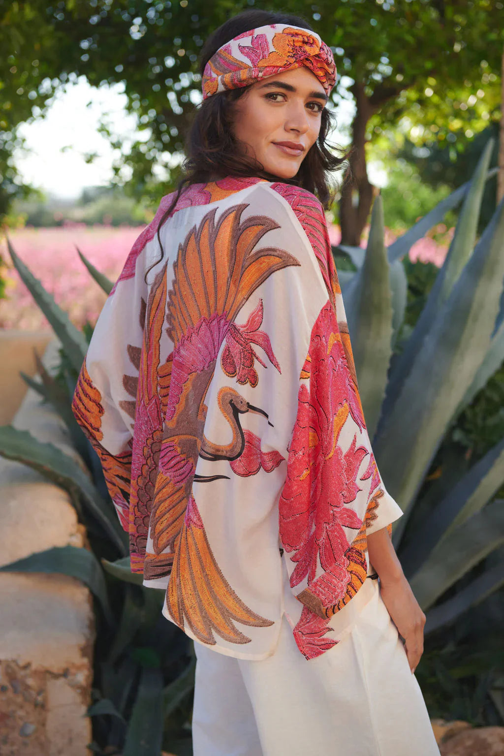 Crane Ecru Kimono: woman in off-white top with orange pink bird motifs