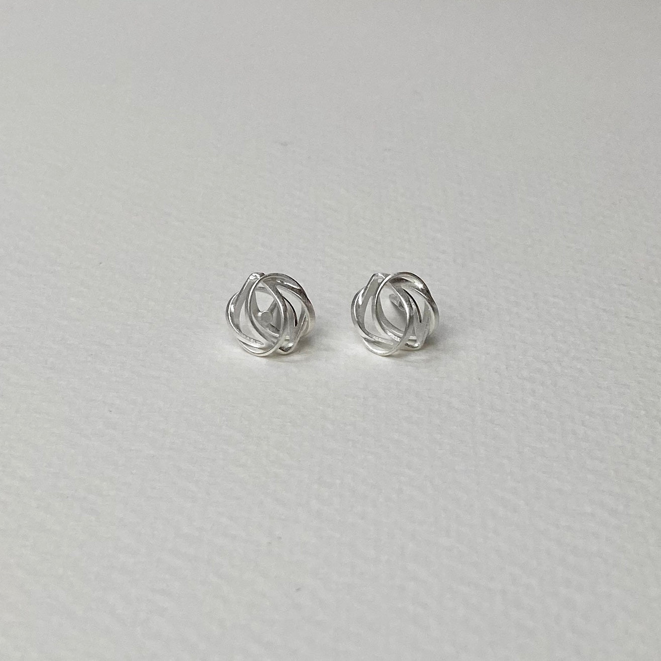 Delicate silver knot earrings with minimalist intertwined wire loops