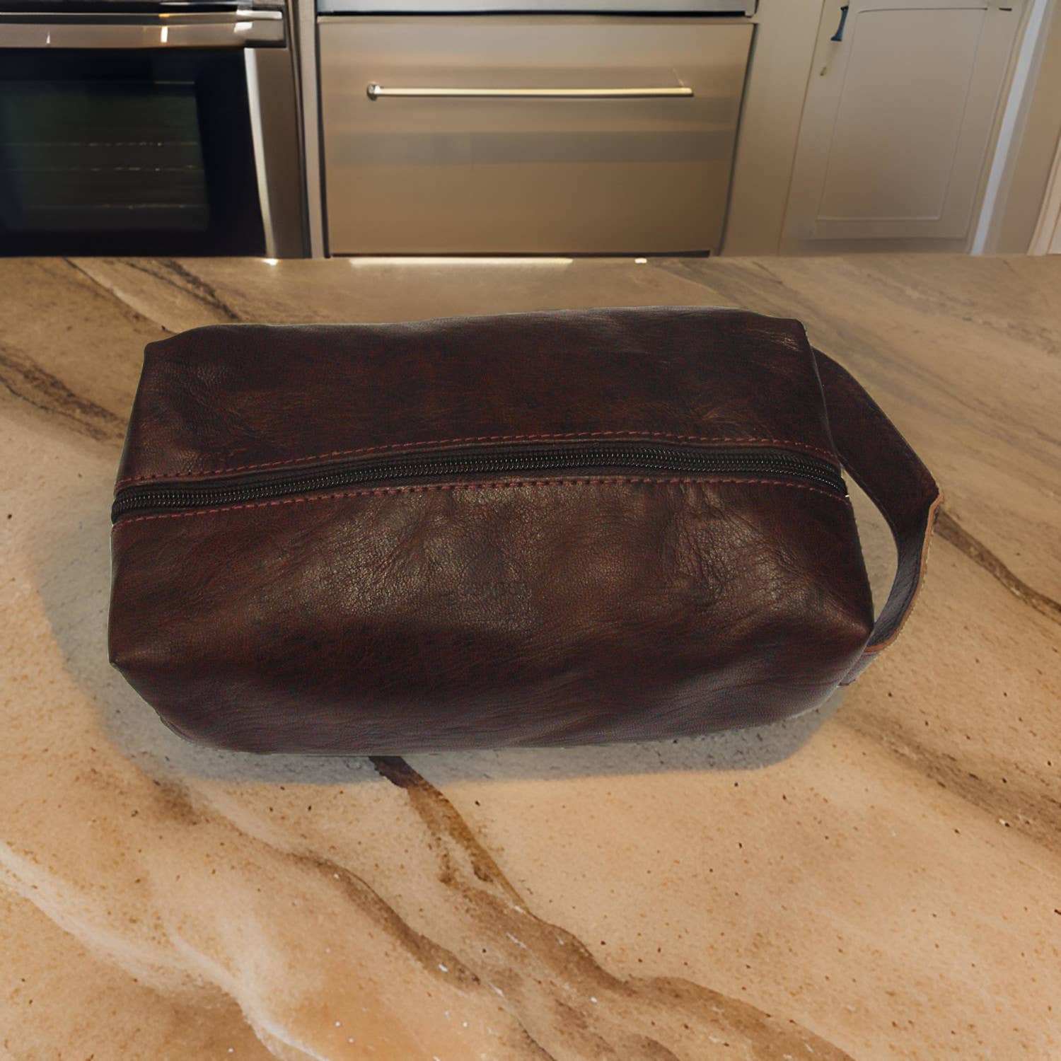 Handmade brown leather wash bag with black zipper and red stitching