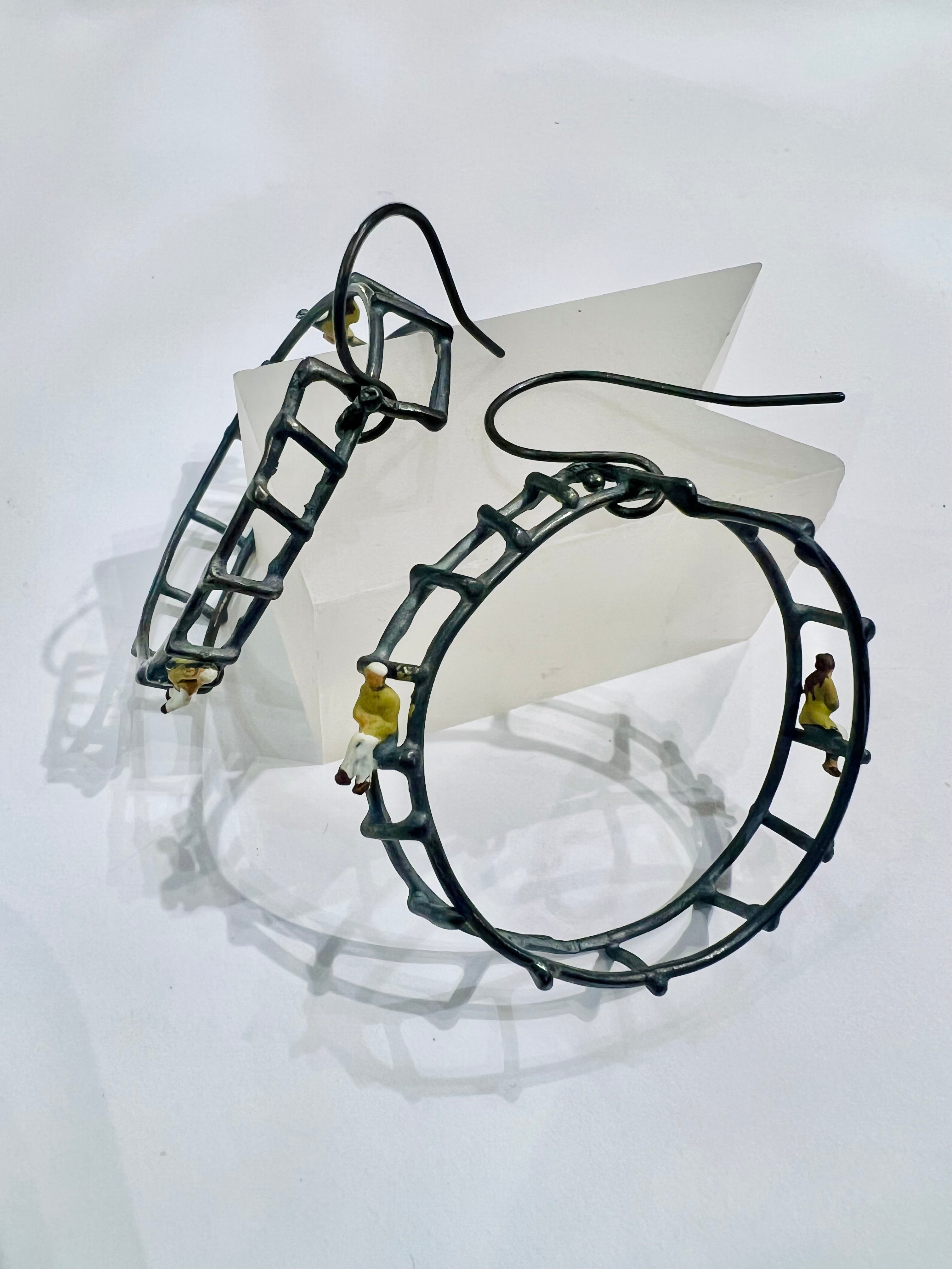 Black metal hoop earrings with yellow-shirted figures climbing ladder design