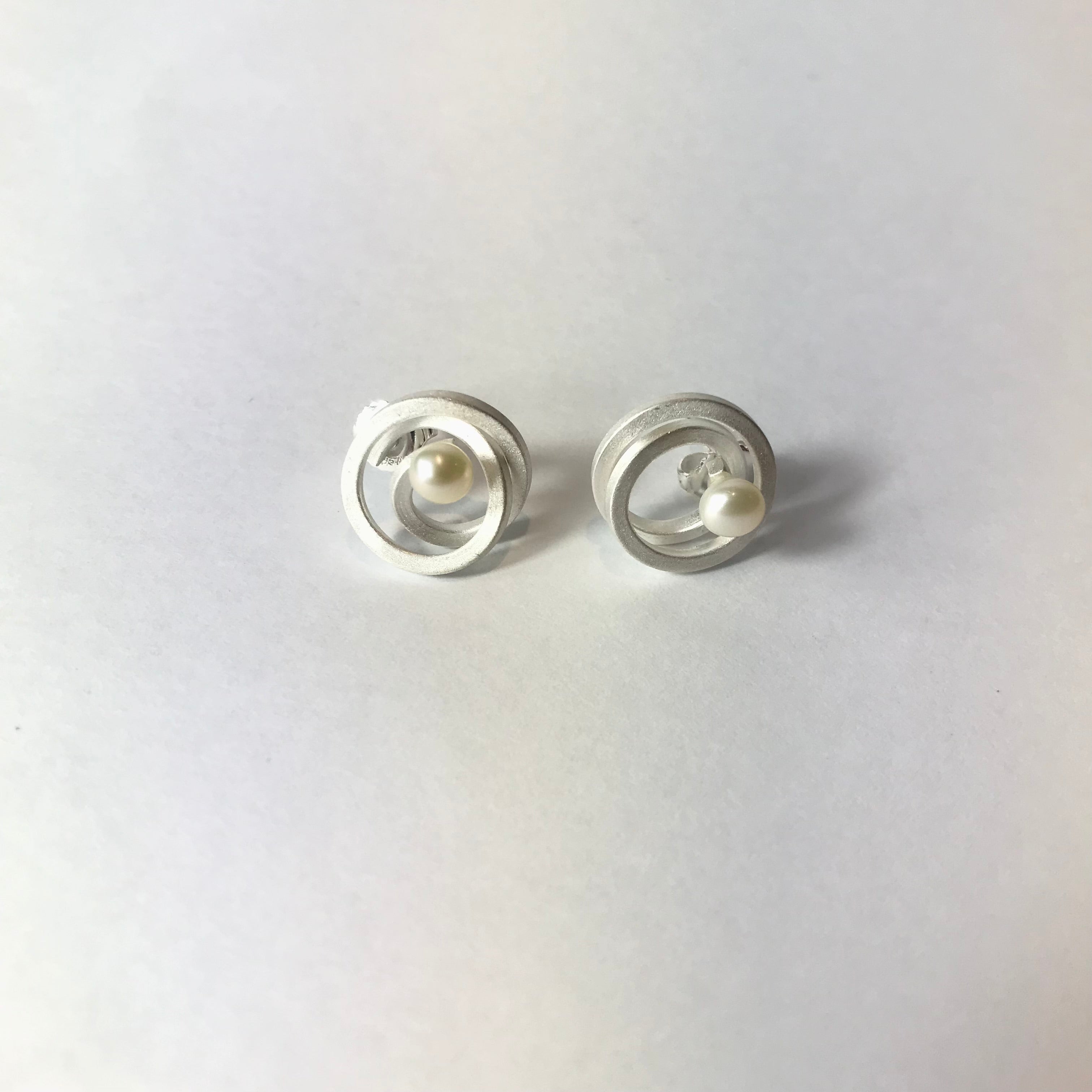 Silver hoop earrings with central pearl accent