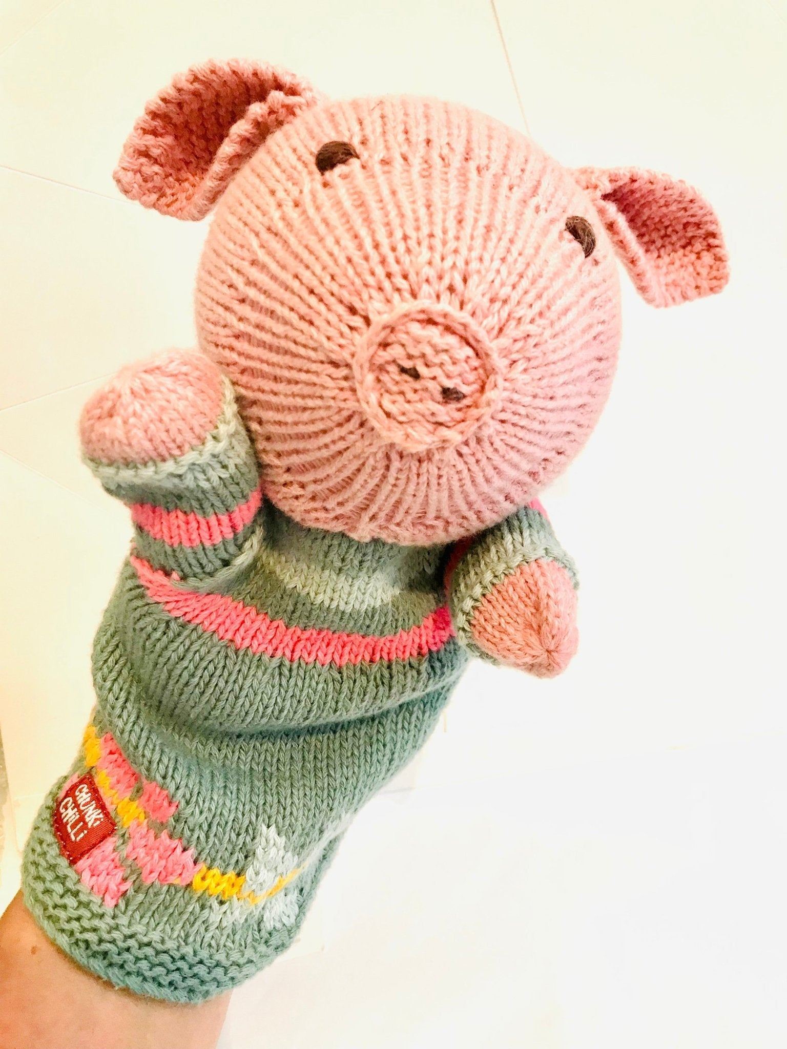 Pink knitted pig hand puppet in green pink striped sweater