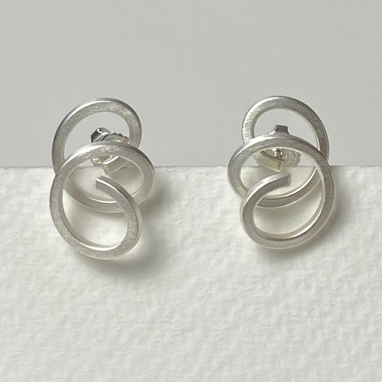 Silver minimalist earrings with interlocking circular rings and satin finish