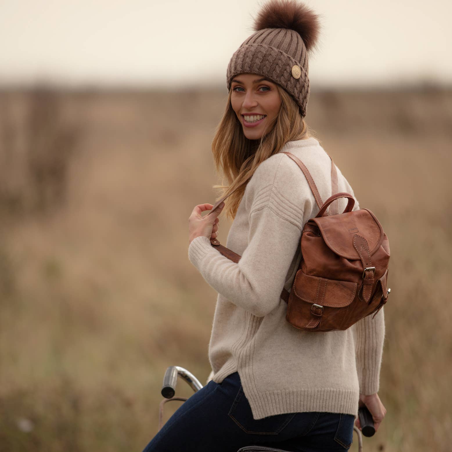 Tan small leather rucksack with brown flap closure and adjustable straps