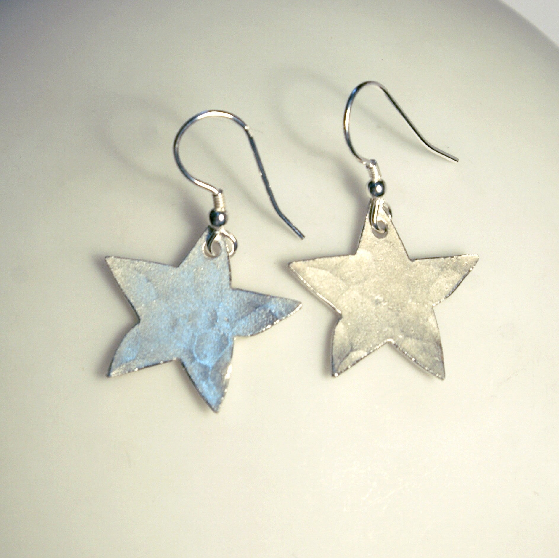Pair of hammered star earrings in light blue and silver