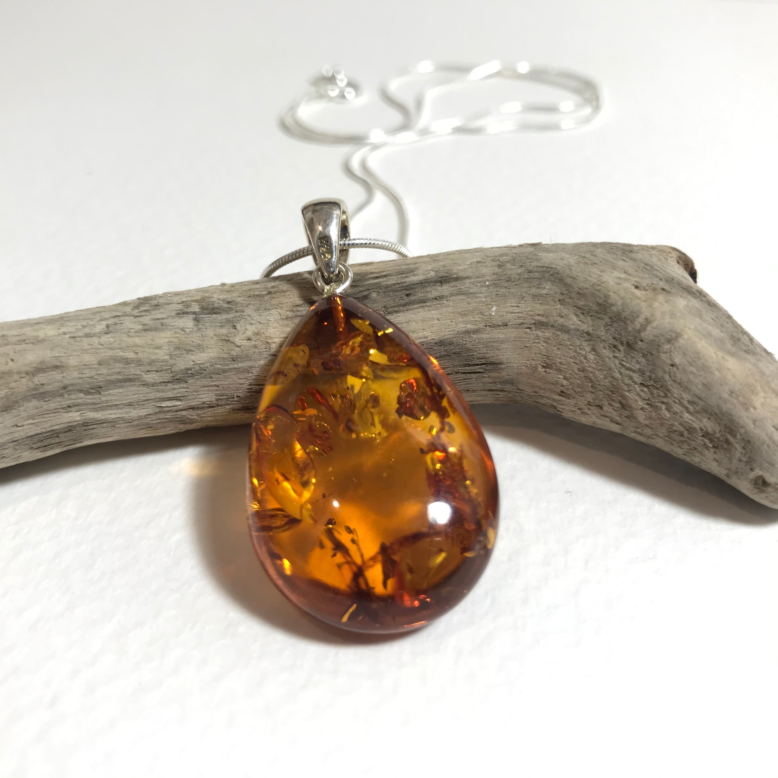 Teardrop amber pendant with botanicals on silver chain