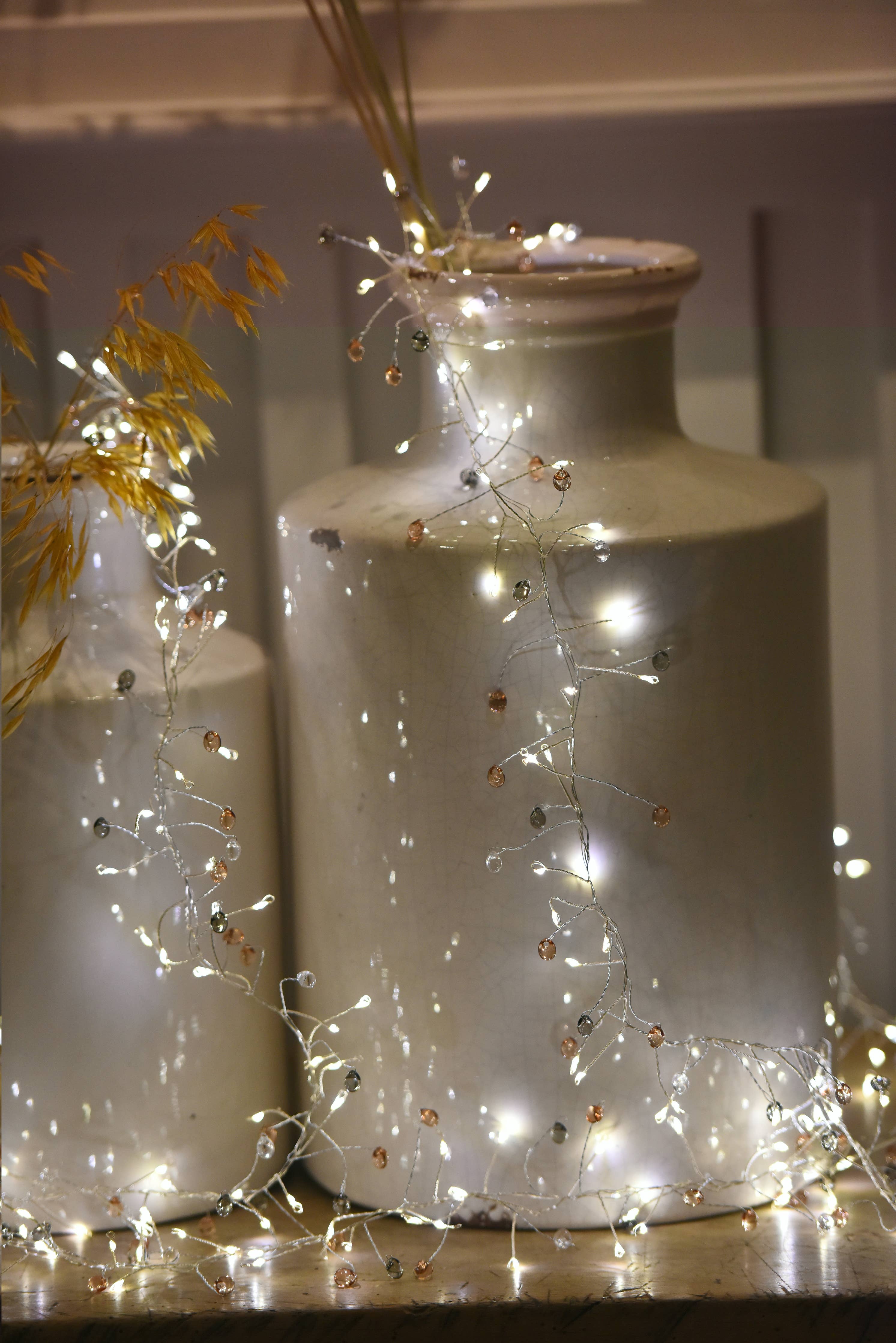 Coco Cluster multi-colour fairy lights draping off-white vase