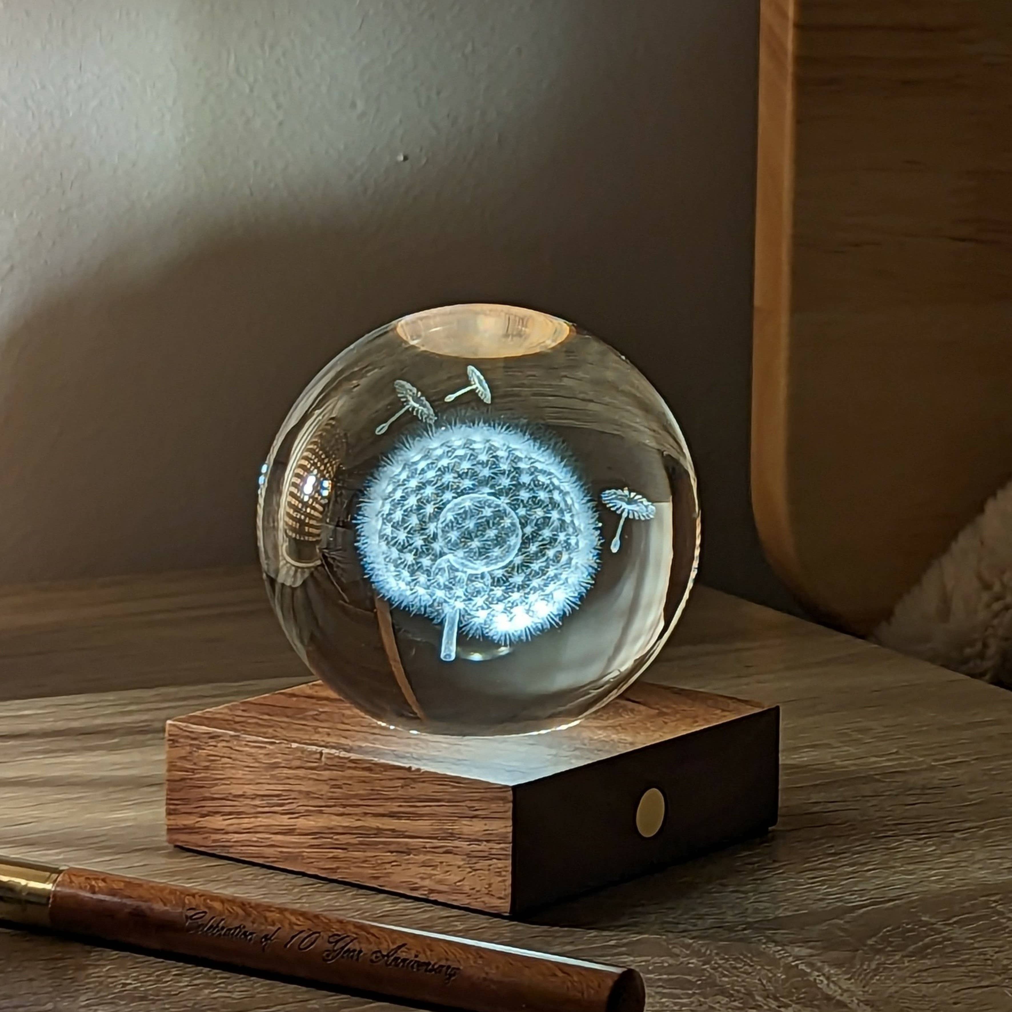 Glowing blue dandelion etched in clear glass sphere on wooden base for Amber Crystal Light