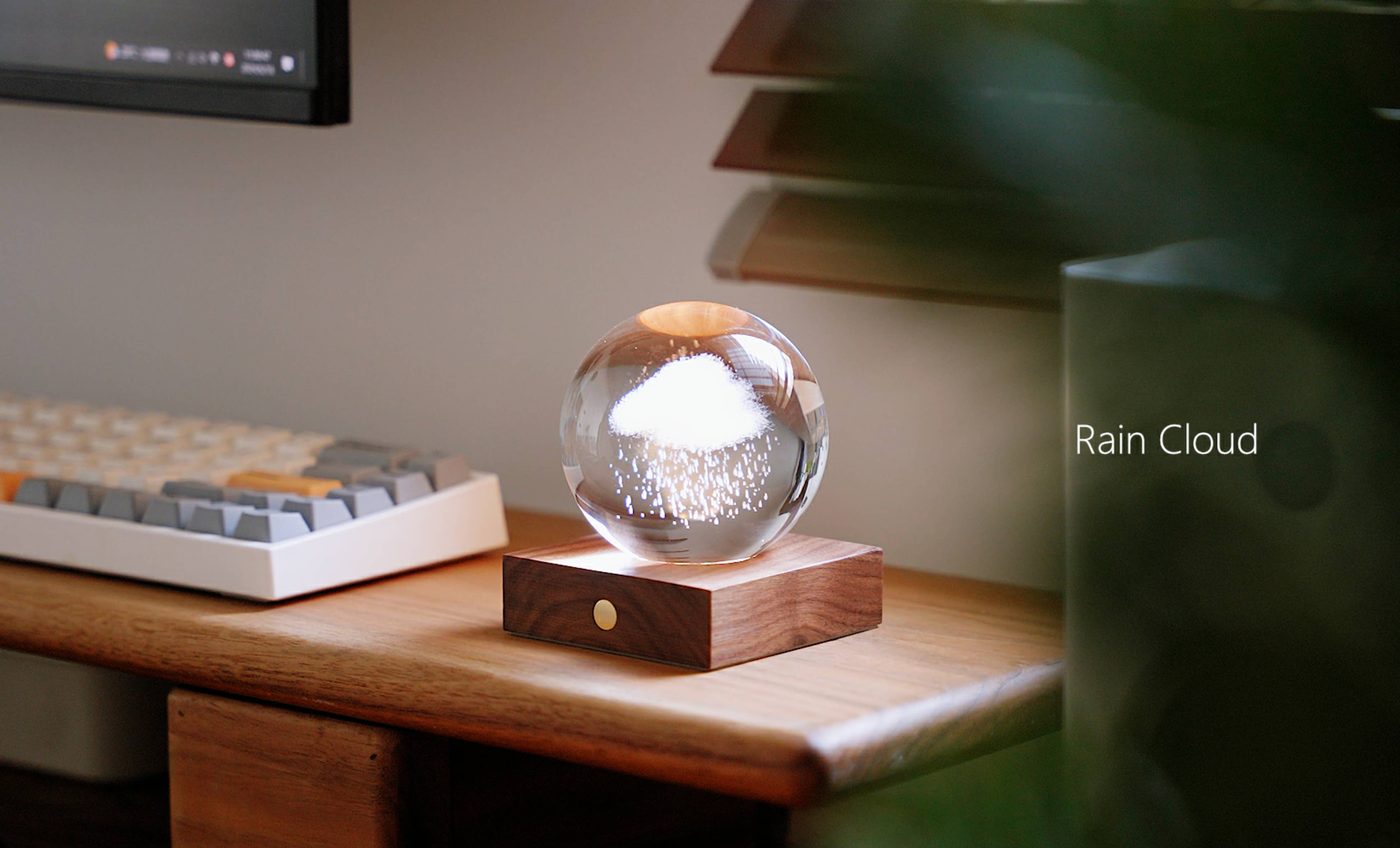 Amber Crystal Light Rain Cloud: clear glass sphere with white cloud and sparkling rain on wooden base