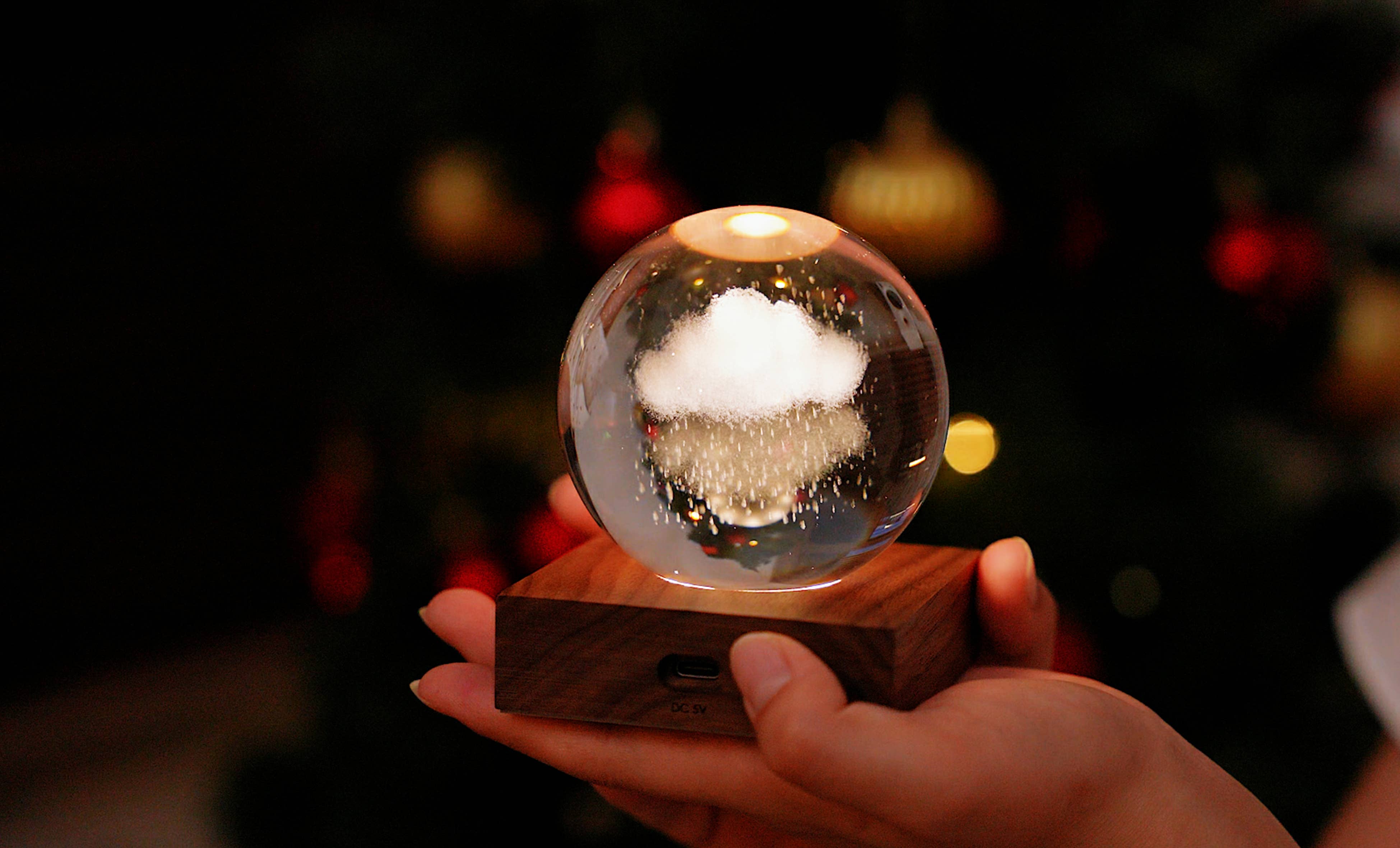 Clear glass snow globe with white cloud, falling glitter on dark wood base in Amber Crystal Light: Solar System