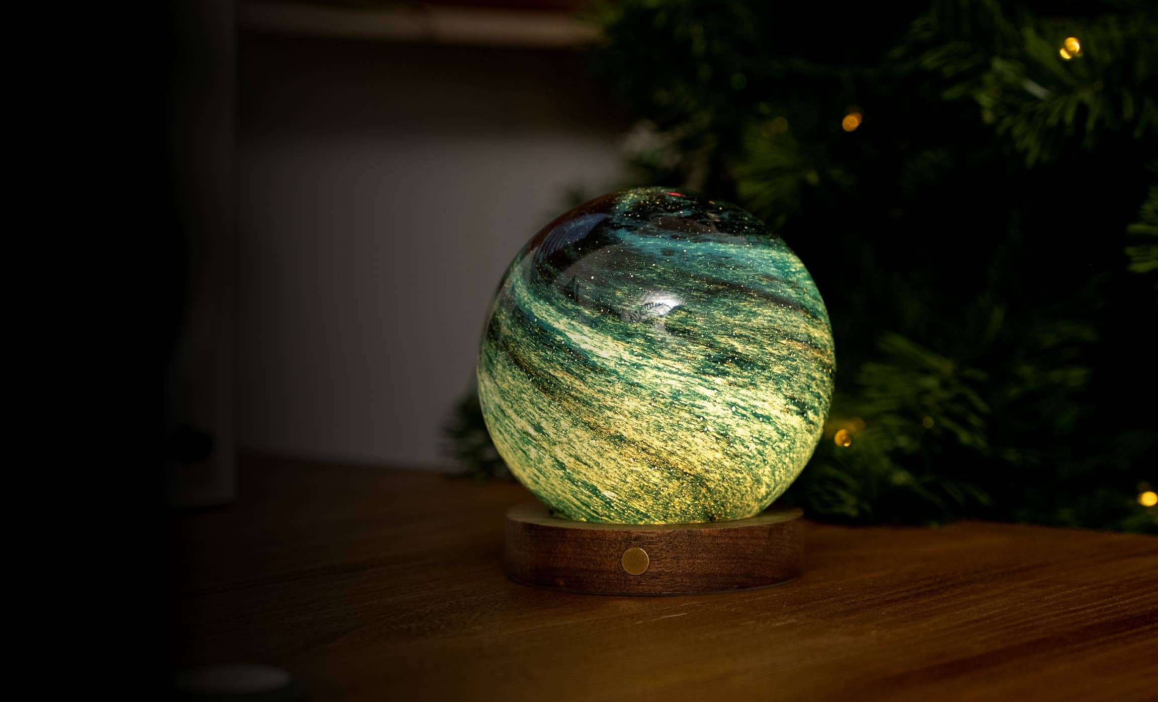 Glowing green and gold resin globe on wooden base, AstraGlass Light Mini Stellar Ocean