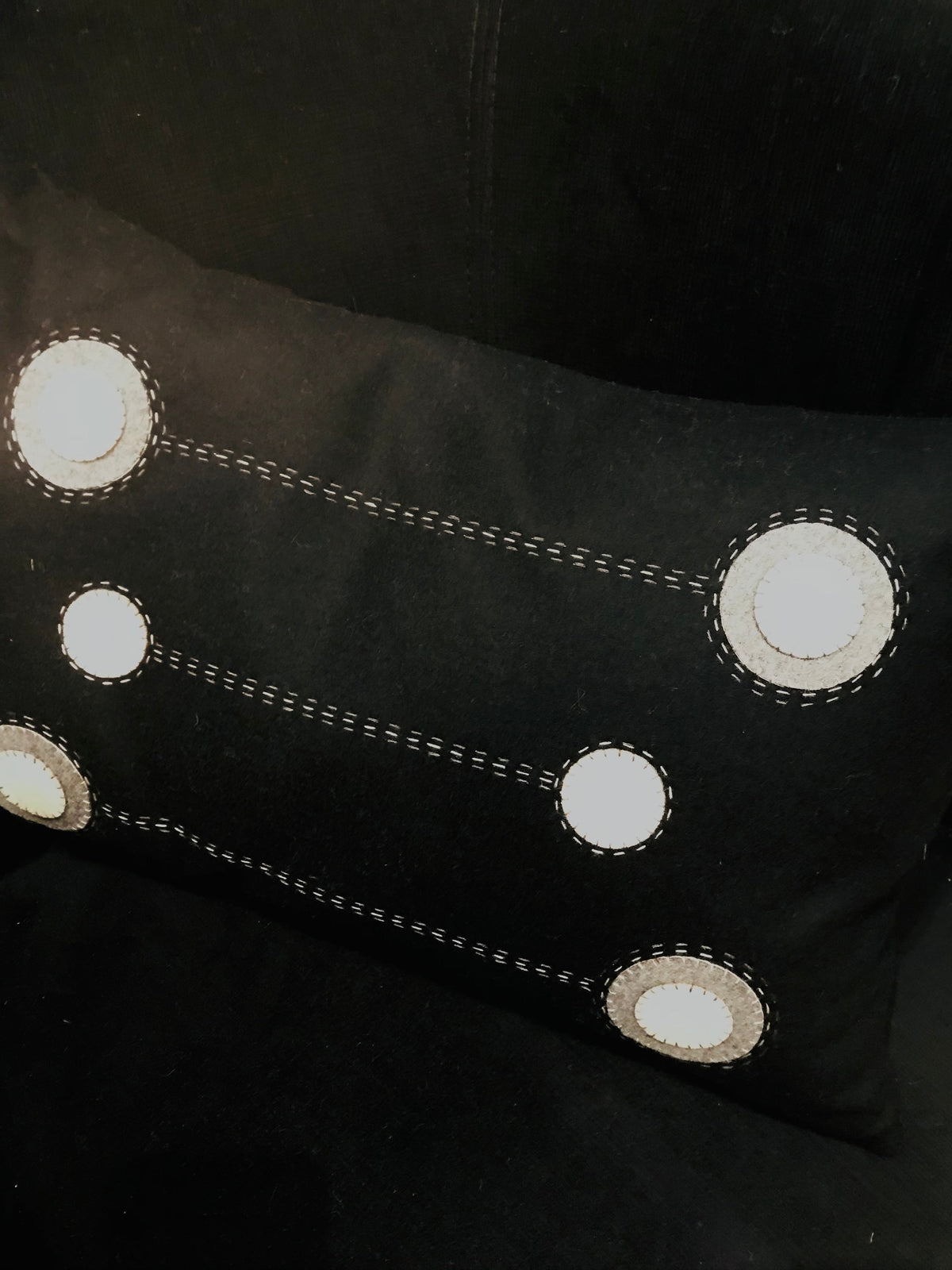 Black wool cushion with embroidered white circular motifs and dashed stitching