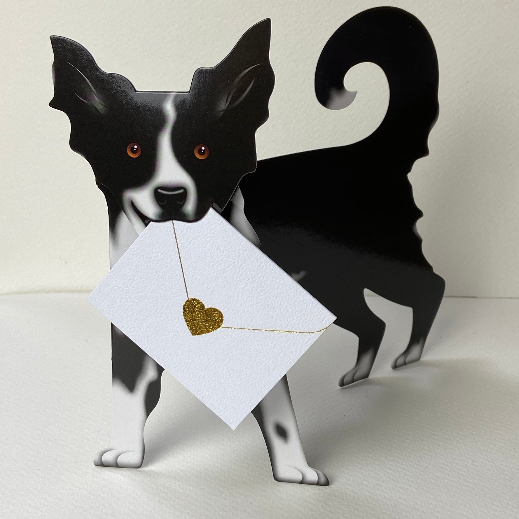 Black and white paper Collie dog holding gold glitter heart card