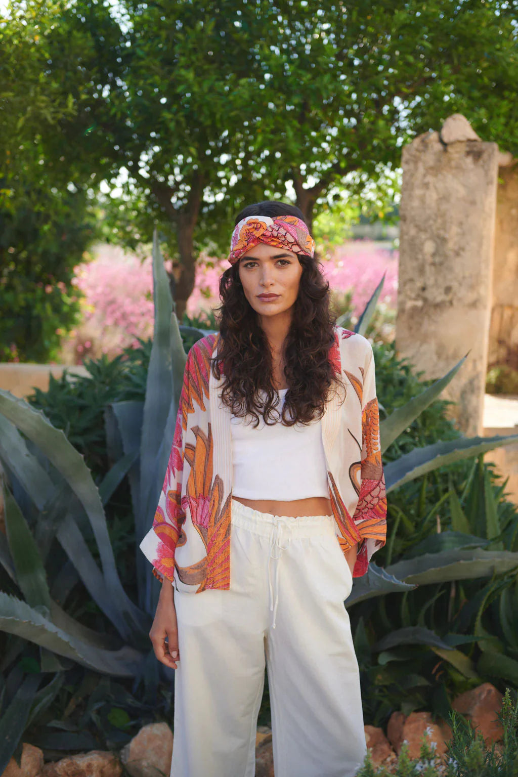 Crane Ecru Kimono: Woman in vibrant orange pink floral jacket over white pants