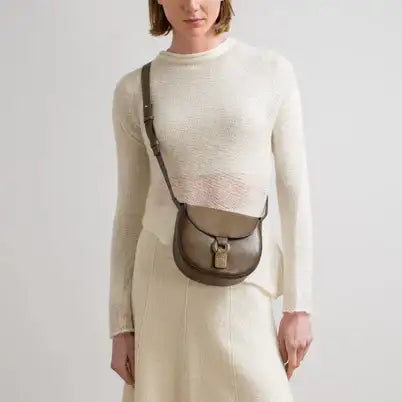 Cream sweater with olive green crossbody bag featuring a leather strap and silver hardware.