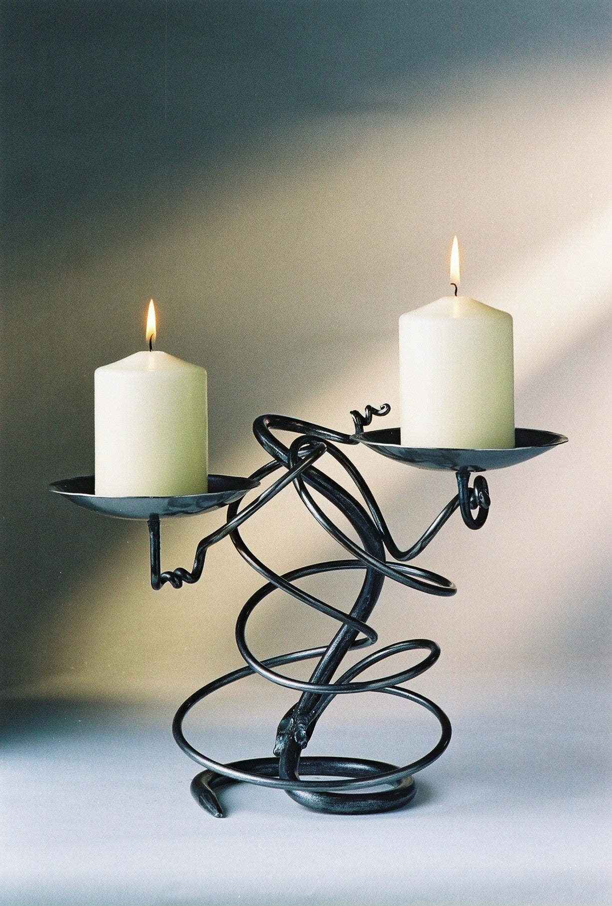 Double Tangle black wrought iron candle holder with curved arms and white pillar candles