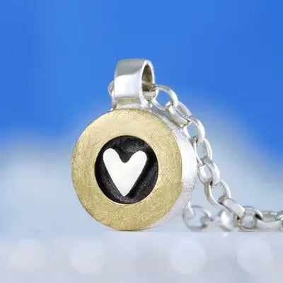Gold and silver heart locket necklace with black enamel background.