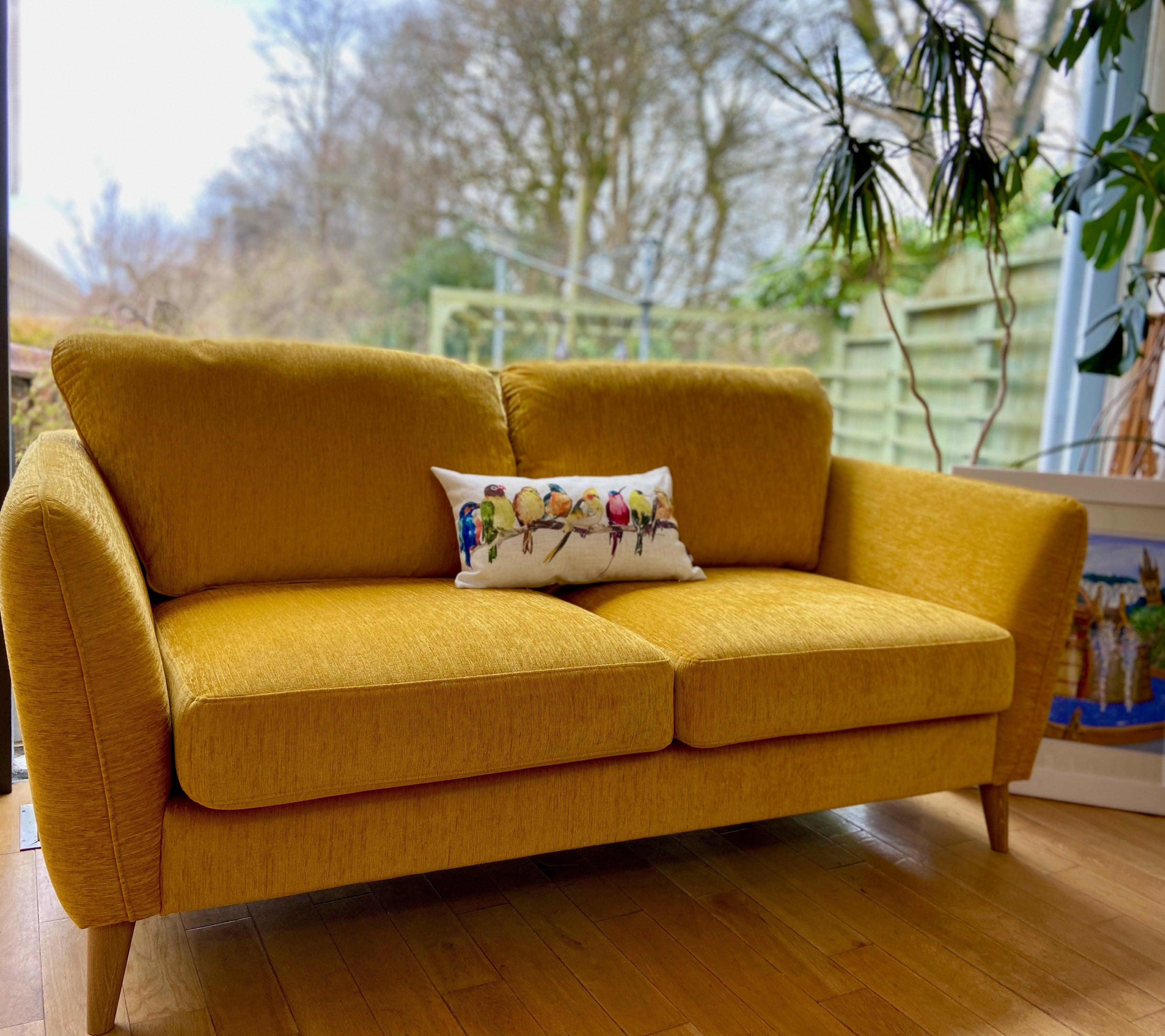 Mustard-yellow Lydia 2-seater sofa with bird pillow and wooden legs