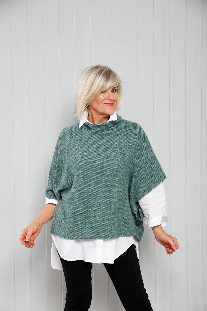Teal knit poncho top with cowl neck and three-quarter sleeves over white shirt