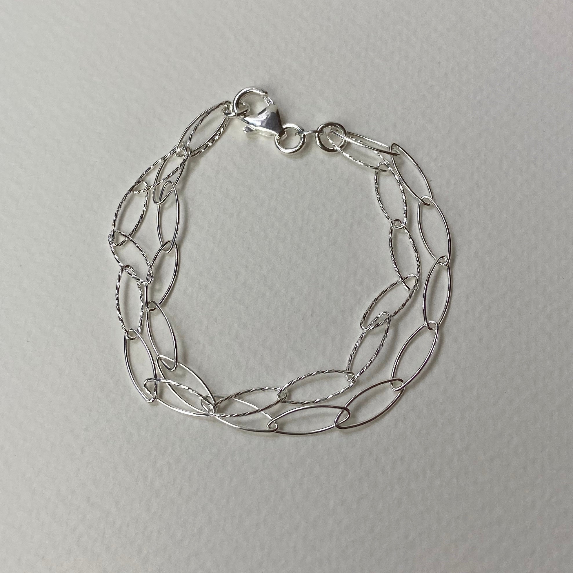 Silver-toned bracelet with interlocking oval links and twisted wire accents