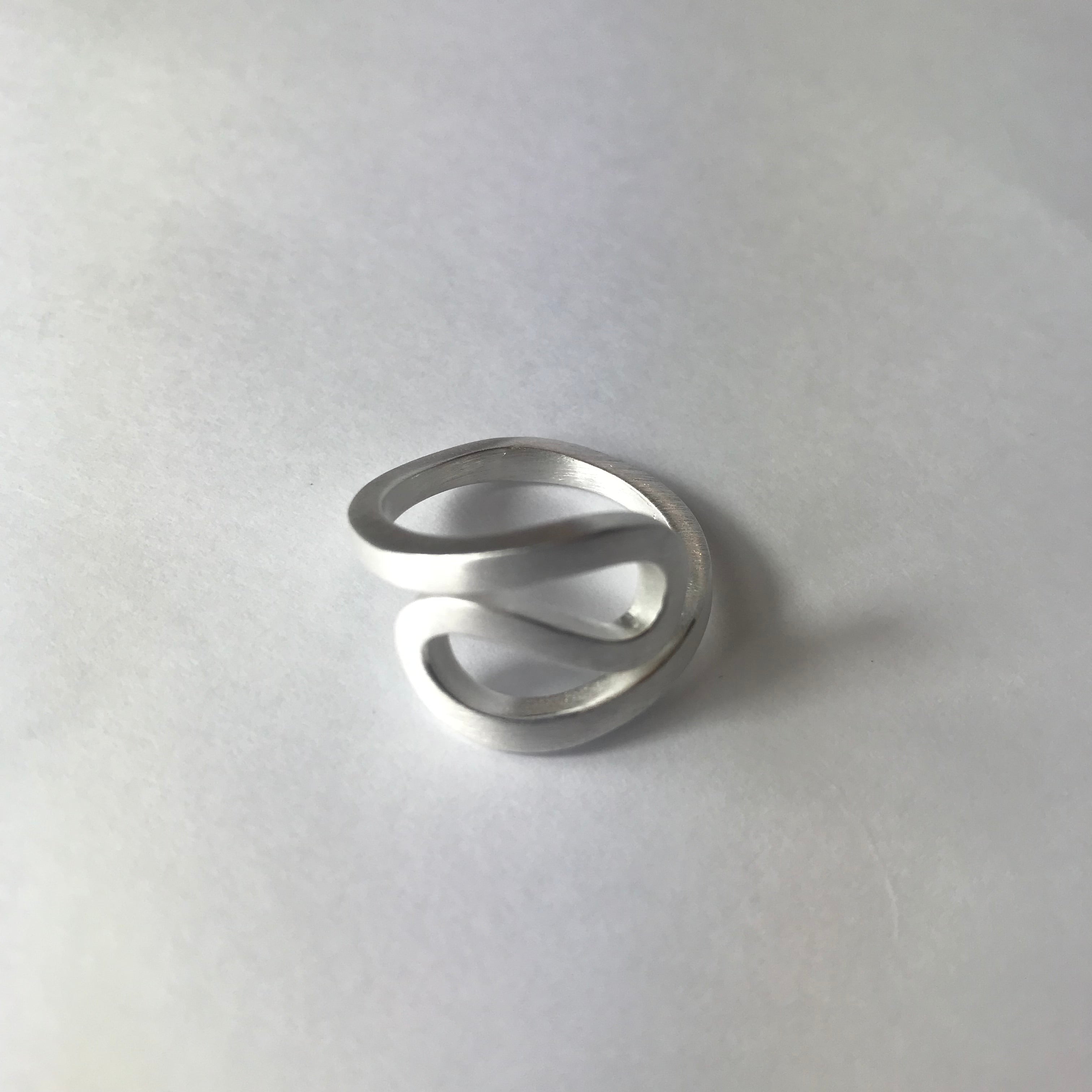 Sleek silver-toned ring with modern open-ended flowing curves